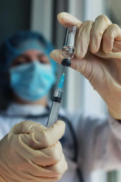 Nurse hands holding syringe and ampoule