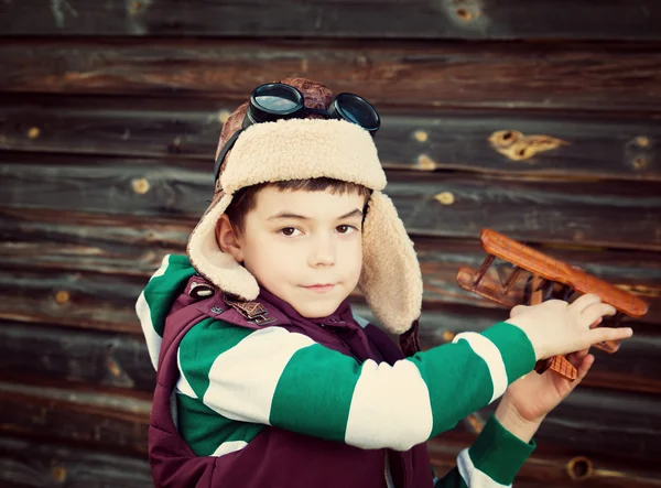 Boy playing in aviator hat with old plane