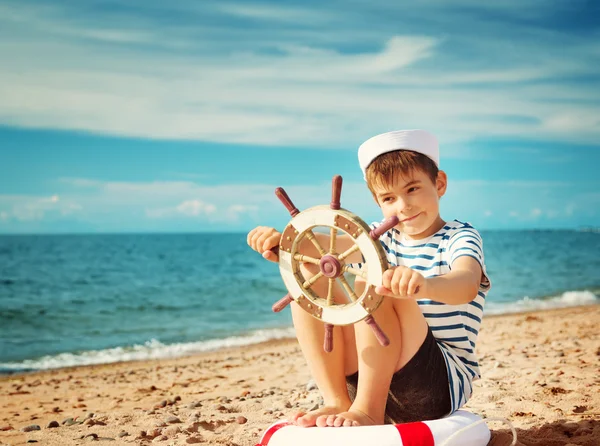Boy playing at the beach with steering wheel