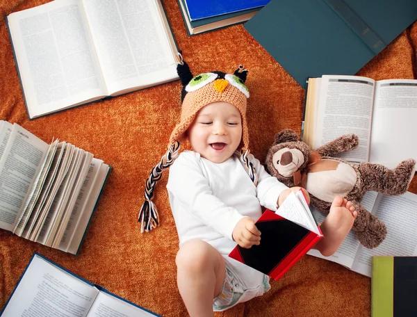 One year old baby reading books with teddy bear