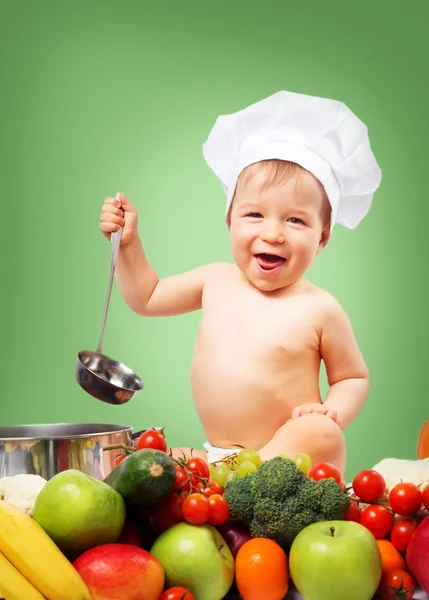 Baby boy in chef hat with cooking pan and vegetables