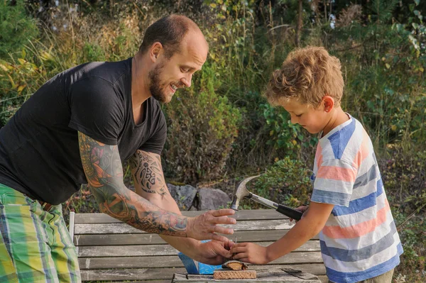 Father teaches son how to hammer a nail