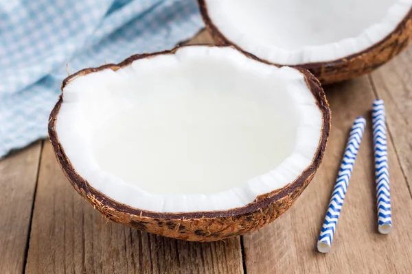 Natural organic coconut water in cracked coconut on wooden table