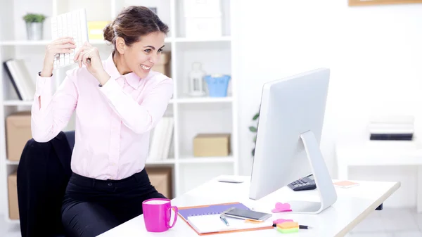 Angry businesswoman about to break computer
