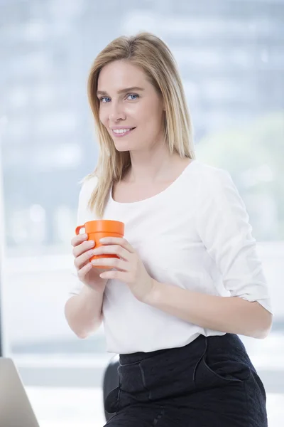 Businesswoman in office drinking coffee