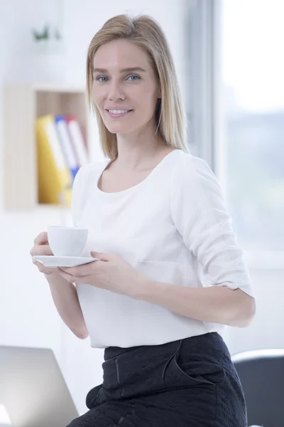 Businesswoman in office drinking coffee