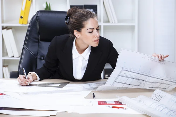 Female architect studying plans in office
