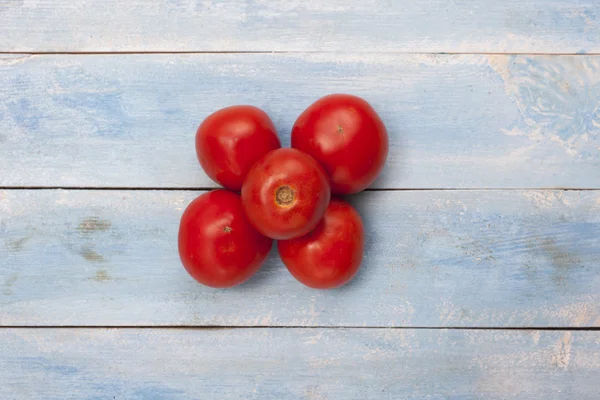 Red organic tomatoes on a blue wooden board, top view