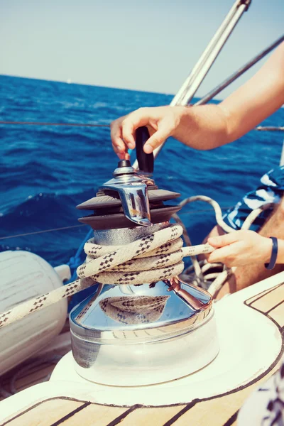 Sailing crew member pulling rope on sailboat