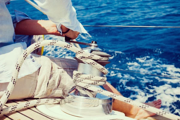 Sailing crew member pulling rope on sailboat