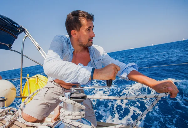 Sailing crew member pulling rope on sailboat