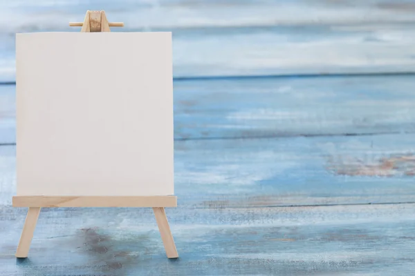 Small easel with album sheet of paper on wooden board