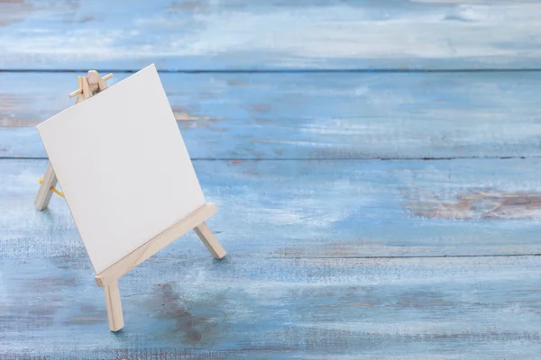 Small easel with album sheet of paper on wooden board