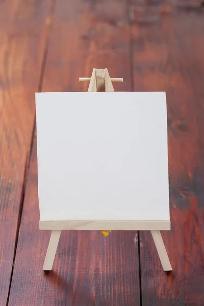 Small easel with album sheet of paper on wooden board