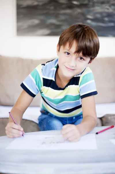 Boy at the table draw on paper drawings using markers