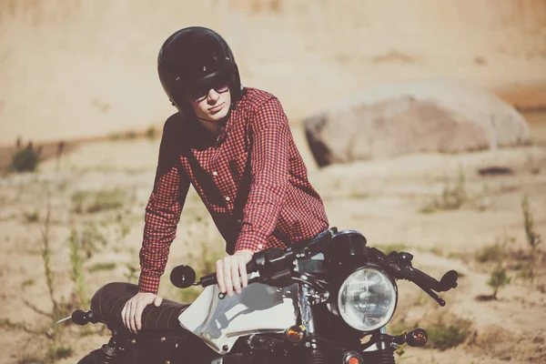 Biker with helmet start a vintage custom motorcycle. Outdoor lifestyle toned portrait