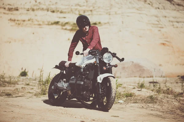 Biker in the desert gets his old custom bike. Vintage motorcycle
