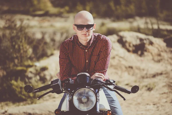 Bald man with glasses sitting on an old vintage custom bike
