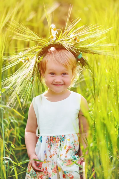 Beautiful girl with wreath on his head in wheat field. Portrait close up.