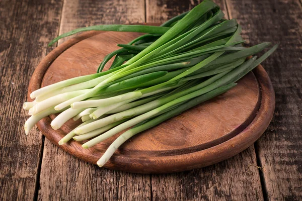 Spring onions also known as salad onions, green onions or scallions on wood background