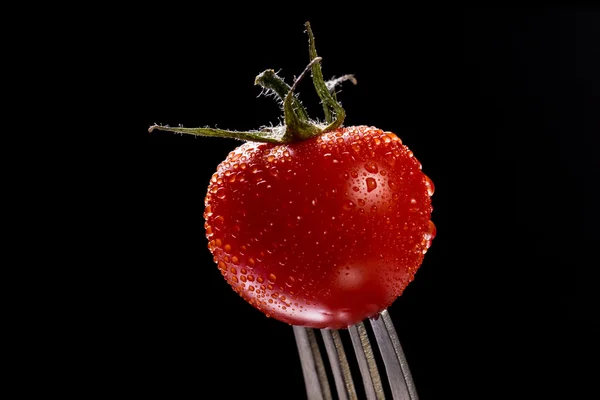 Tomato single with drops isolated on black