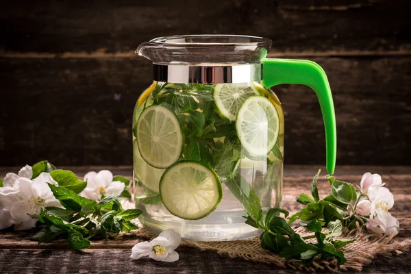 Detox water with a lemon, lime and mint on a wooden table