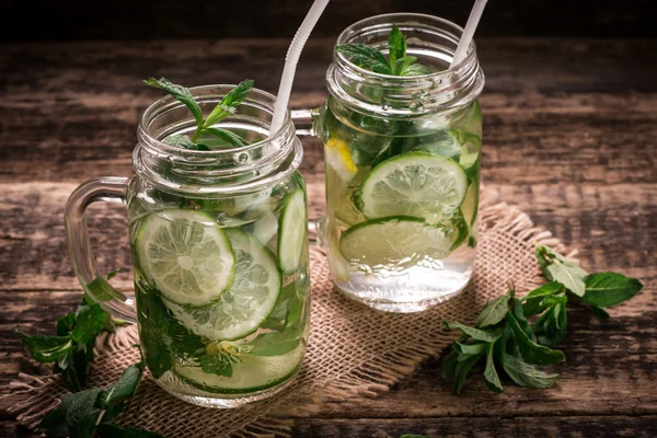 Detox water with a lemon, lime and mint on a wooden table