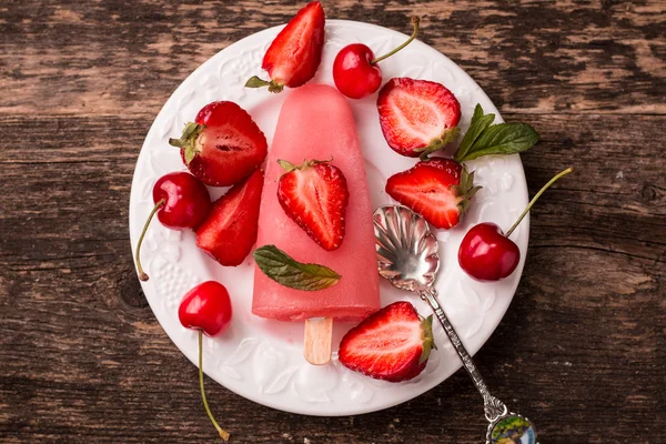 Refreshing fruit popsicle lollies on wooden table with berries and fruits