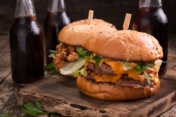 Fast food with burger or cheeseburger, and soft drink on vintage wooden table