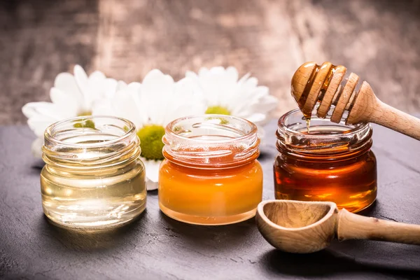 Honey in jar with honey dipper on black stone background