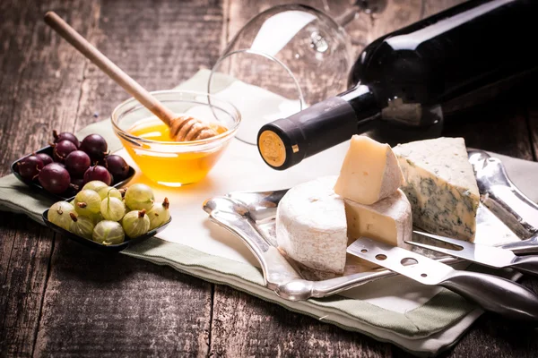 Composition of cheese, berries, bottles and glasses of wine on a wooden table