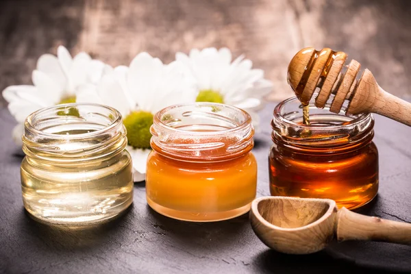 Honey in jar with honey dipper on black stone background