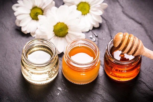 Honey in jar with honey dipper on black stone background