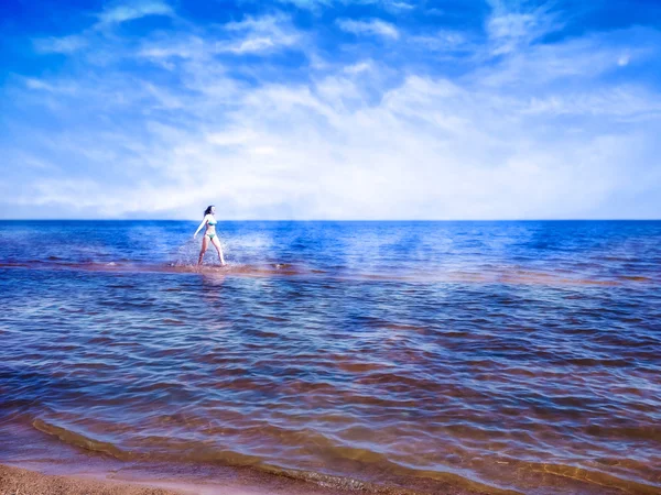 Beautiful girl running on shining water of blue sea