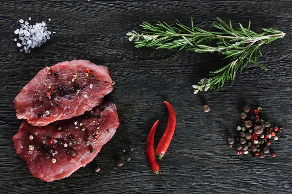 Two garnished raw beef steaks