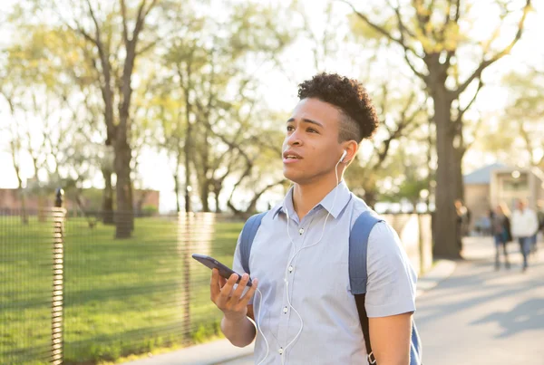 Hispanic college student talks on the smartphone with earbuds