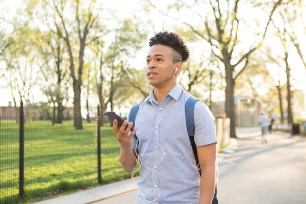 Hispanic college student talks on the smartphone with earbuds
