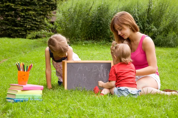 Mother teaches her young children letters