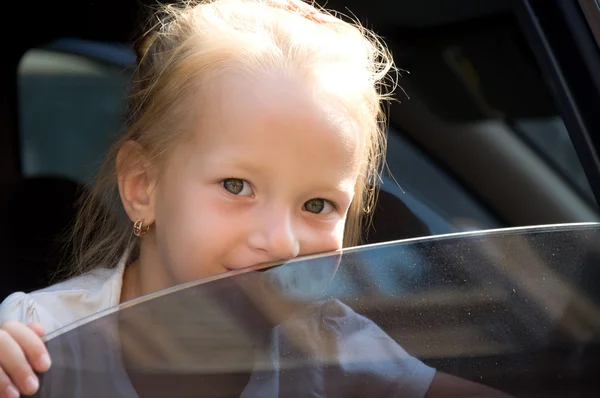 Little girl sitting in a car and looking out the window