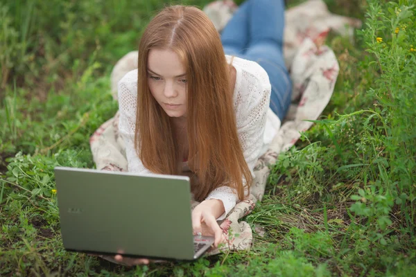 Young serious woman student girl with notebook in park looking at notebook computer