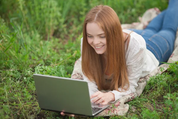 Young smiling woman with notebook in park looking at notebook computer.
