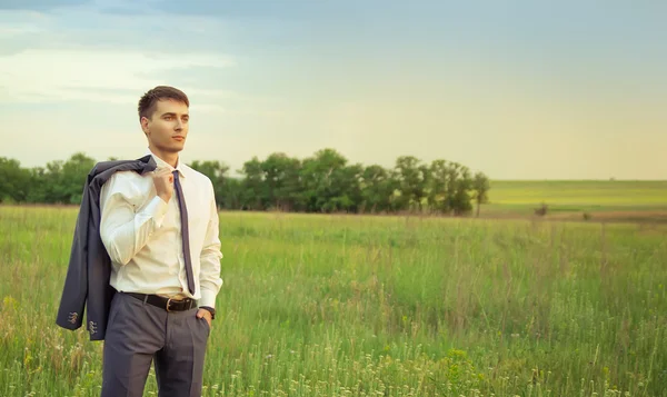 Businessman standing in field and looking forward