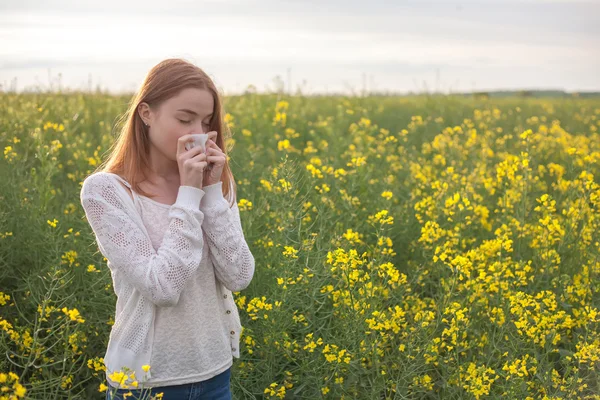 Pollen allergy, girl sneezing in a field of flowers