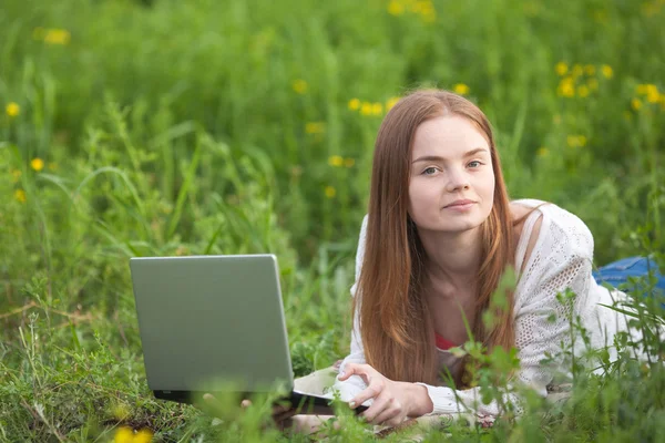 Young smiling woman with notebook in park looking at notebook computer.