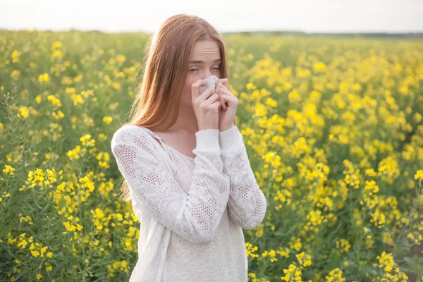 Pollen allergy, girl sneezing in a field of flowers