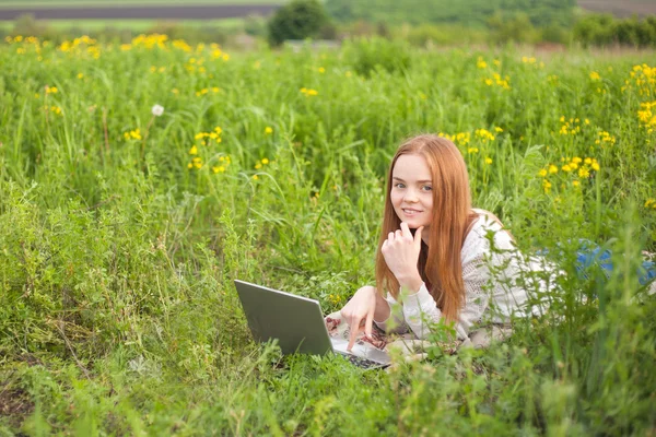 Young smiling woman with notebook in park looking at notebook computer