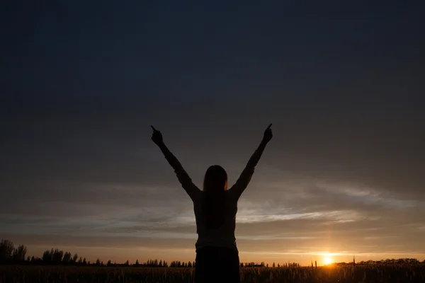 Woman with open arms in the green wheat field at the morning.