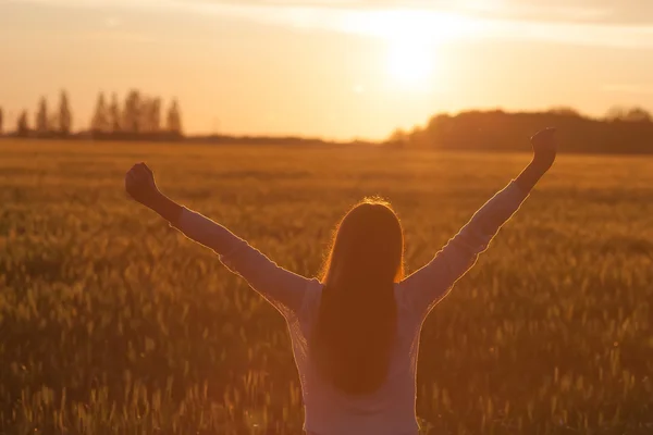 Woman with open arms in the green wheat field at the morning.