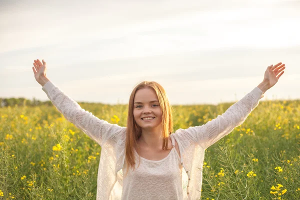 Woman with open arms in the green rapeseed field at the morning.