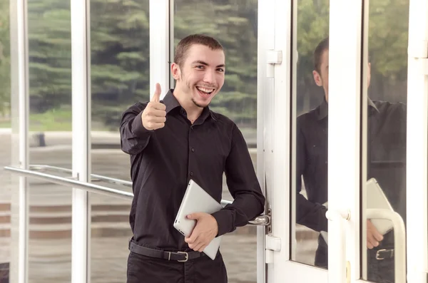 Happy businessman with digital tablet makes a gesture thumb up in the office.